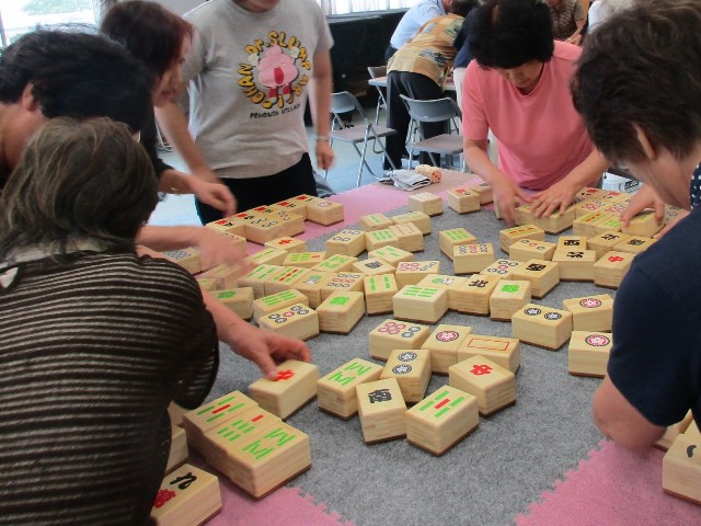 牌が机に散らばり助け合いながら並べている 牌が机に散らばり助け合いながら並べている